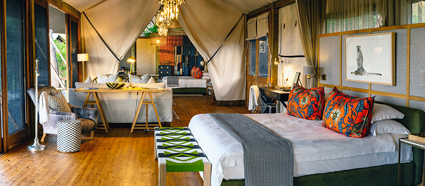 Spacious and stylish safari tent interior at Tuludi Camp, featuring vibrant décor, a king-sized bed, and elegant furnishings.