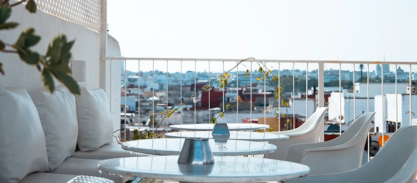 Rooftop terrace seating with white chairs and tables overlooking Rabat’s Medina rooftops under bright daylight.