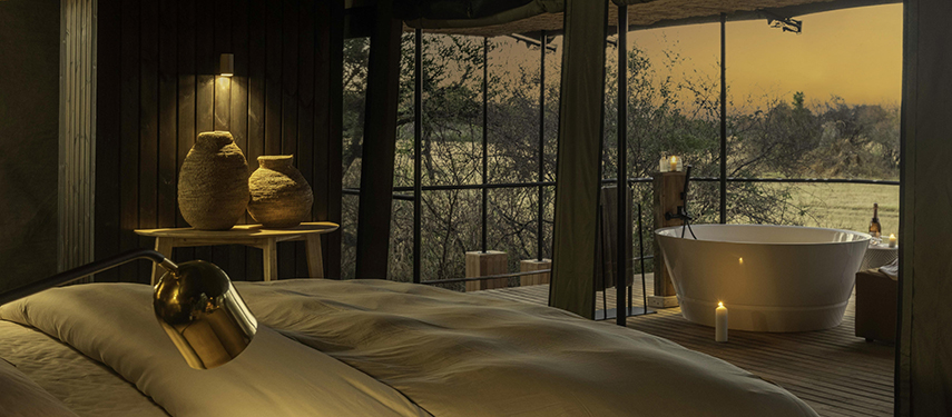 Interior view of a luxury tent at Kiri Camp featuring a freestanding bathtub and open-air deck.