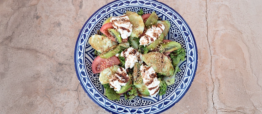 Colourful Moroccan salad with fresh tomatoes, cheese, and sesame seeds served in a patterned ceramic bowl.