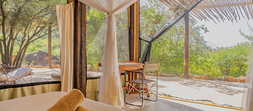 Light-filled bedroom at Reteti House with floor-to-ceiling mesh windows and natural wooden features.