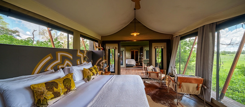 A family tent interior features two connected bedroom spaces with wide mesh windows framing the Delta landscape.