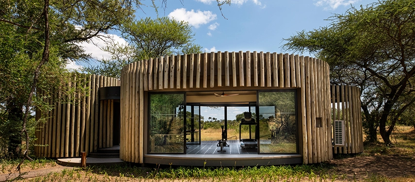 Exterior of the circular, wood-slatted gym pod at Tanda Tula with glass doors opening to the bush.