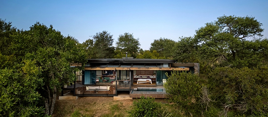 Front view of a Tanda Tula suite nestled in the trees, showcasing the glass walls, private deck, and plunge pool.