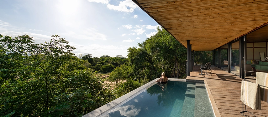 A guest relaxing in a private plunge pool on the deck of a Tanda Tula suite, overlooking the riverbed.