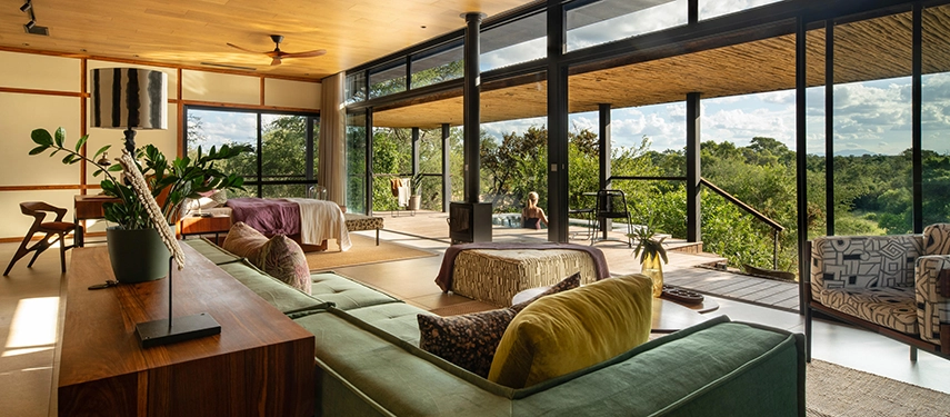 A wide shot of the open-plan suite interior, showing the lounge, bedroom, and seamless connection to the outdoor deck.