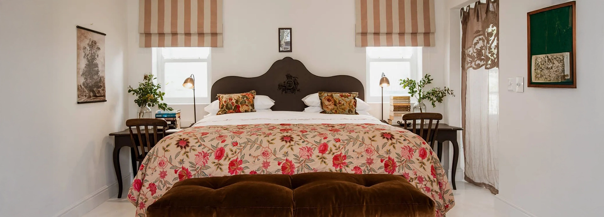 Elegant bedroom at Dorp Hotel with floral textiles, soft lighting, and French doors opening to sweeping views of Table Mountain.