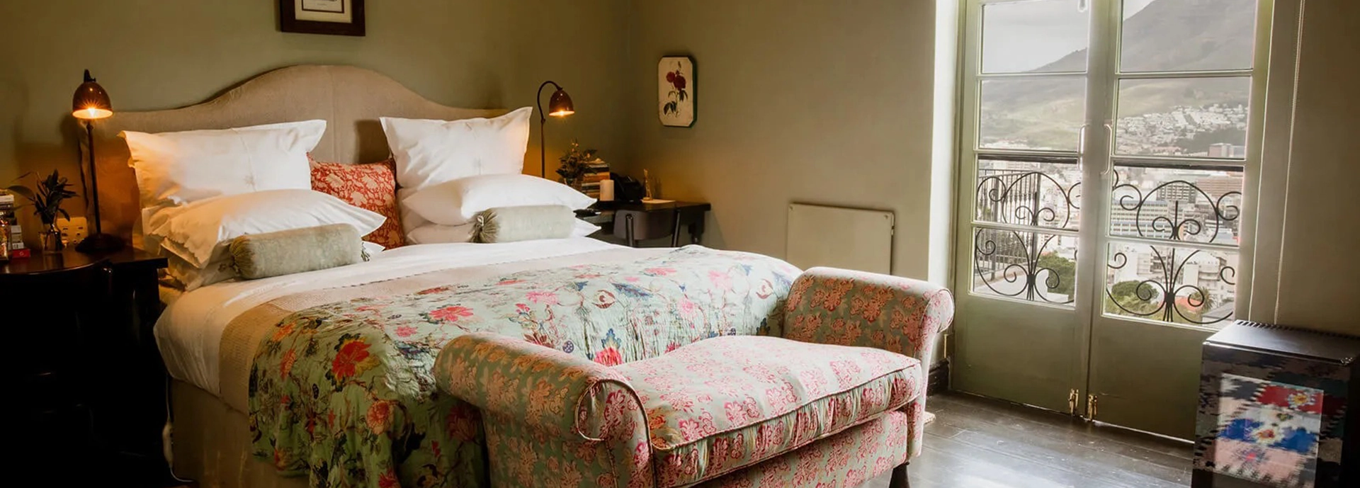 Hillside view of Dorp Hotel’s whitewashed buildings surrounded by trees, overlooking Cape Town’s skyline and Table Mountain.