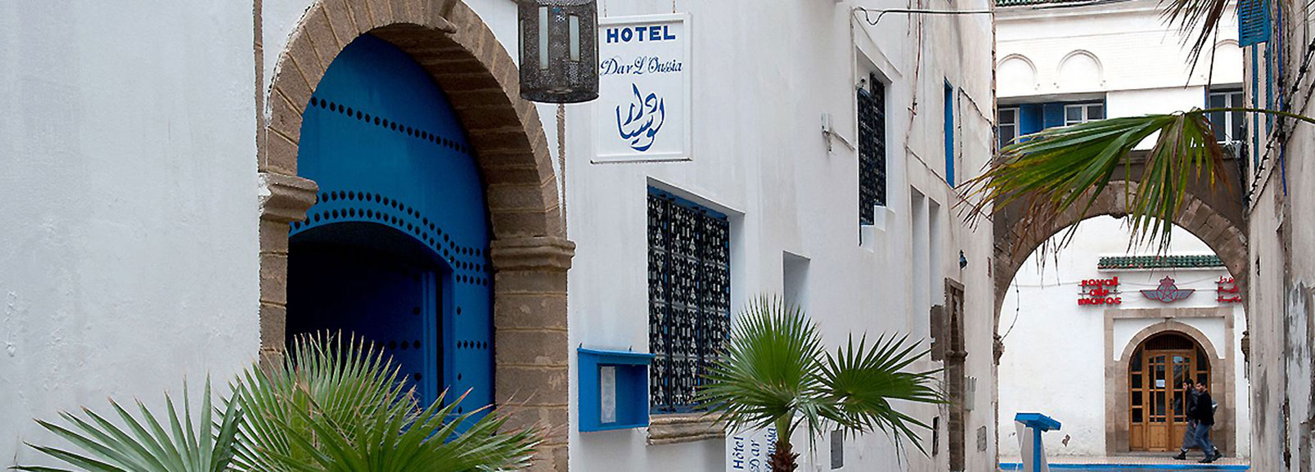 The entrance at Dar L'Oussia features a classic blue coloured door, framed by small palm trees