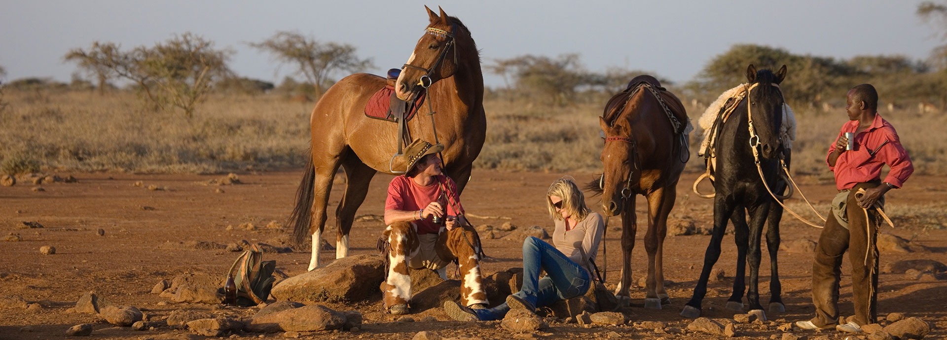 A couple and their horses sit with their Maasai guide in Kenya's northern regions