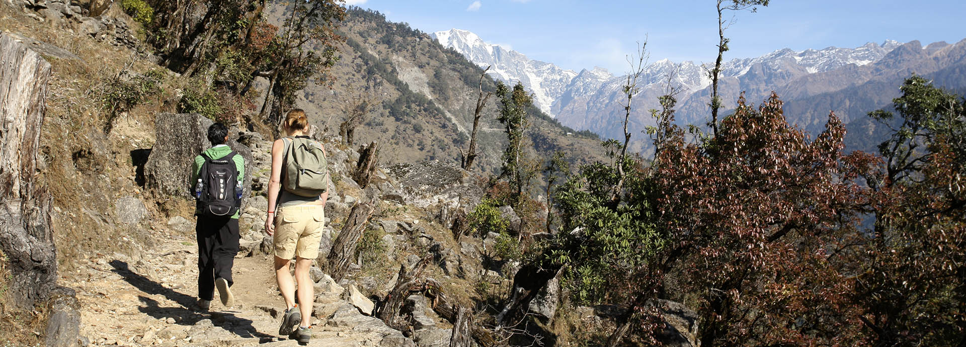 A Western woman and guide hiking through the foothills of the Himalayas