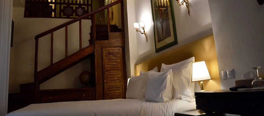 A characterful duplex-style room with wooden stairs, traditional furnishings, and a comfortable double bed.
