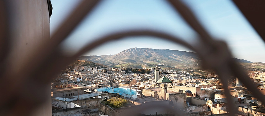 View of Fes medina and surrounding hills seen through a decorative lattice from Dar Bensouda’s rooftop.