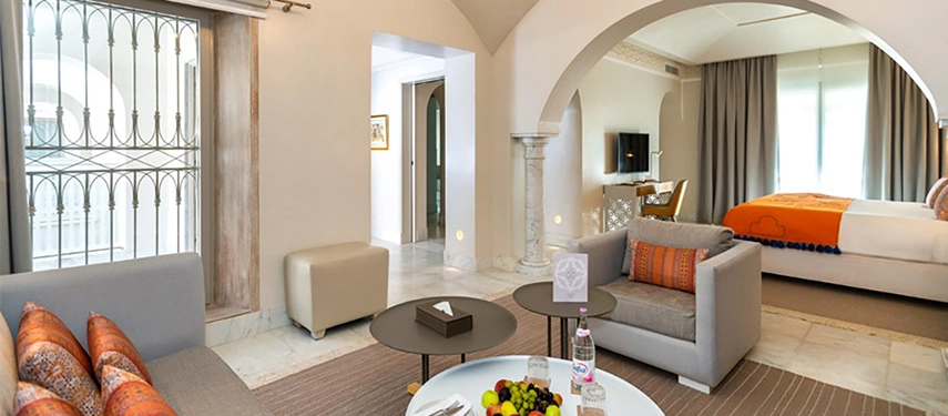 Bright suite with arched layout, lounge area, and fruit platter set for arrival.