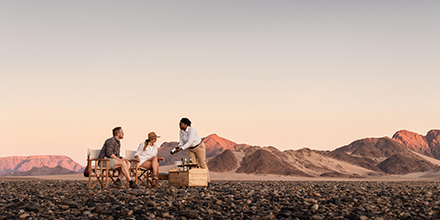 Tourist couple is served snacks by a waitress at Kulala Desert Lodge, Namibia