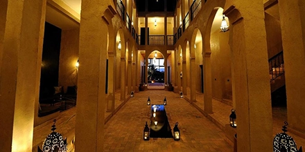 Atmospheric evening view of Dar Chamaa’s arched courtyard lit by lanterns.