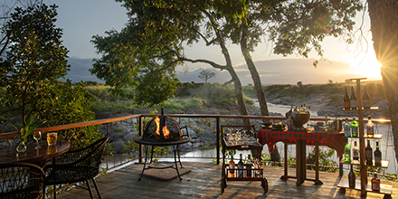 A sundowner setup with drinks and fire pit overlooking the river at sunset.