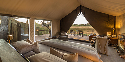 Interior view of a tented suite at Little Machaba featuring twin beds, a writing desk, and a private deck overlooking the floodplain.