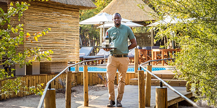 Waiter serving wine at a luxury safari camp in Botswana