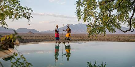 Two Samburu warriors reflected in the still water of the infinity pool at Reteti House.