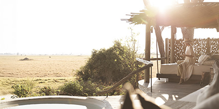 Woman looks out over the grassy plains of the Okavango Delta at sundown at a Little Mombo camp in Botswana