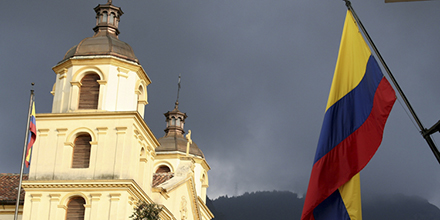 The Colombian flag flying at sunset in Bogotá with elegant Hispanic architecture illuminated in the background