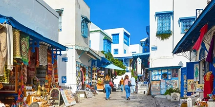 Charming street scene in Sidi Bou Said with whitewashed walls, blue shutters, and colourful market stalls.