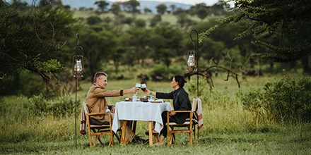 A couple enjoys dinner in the bush while on safari at Usawa Serengeti, Tanzania