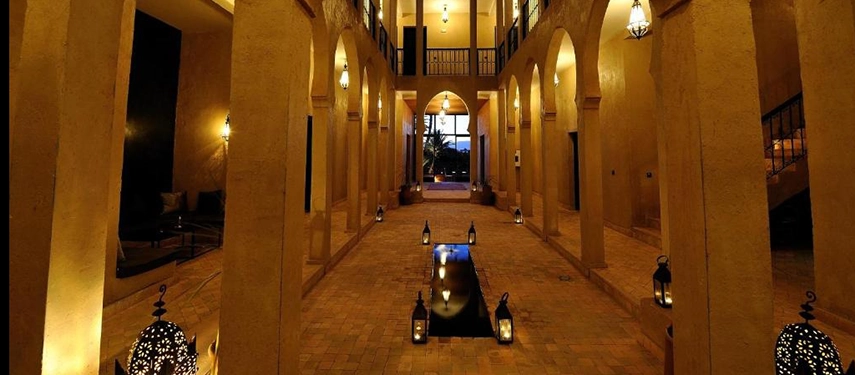 Lantern-lit interior courtyard with arches and a reflecting pool at night.