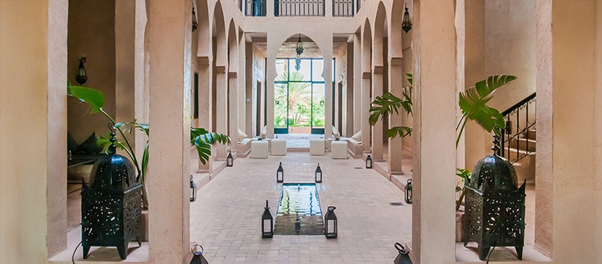 Elegant courtyard seating area with arched doorways, lanterns, and natural light streaming through.