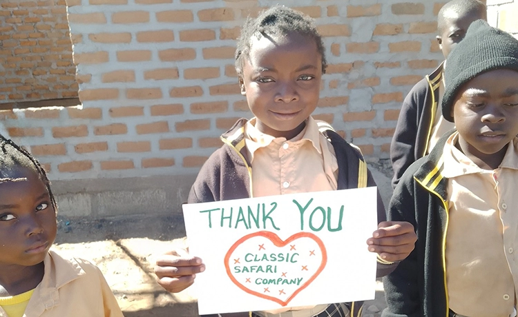 A young student holds a note of thanks for a donation to the Pride Rock Trust by The Classic Safari Company