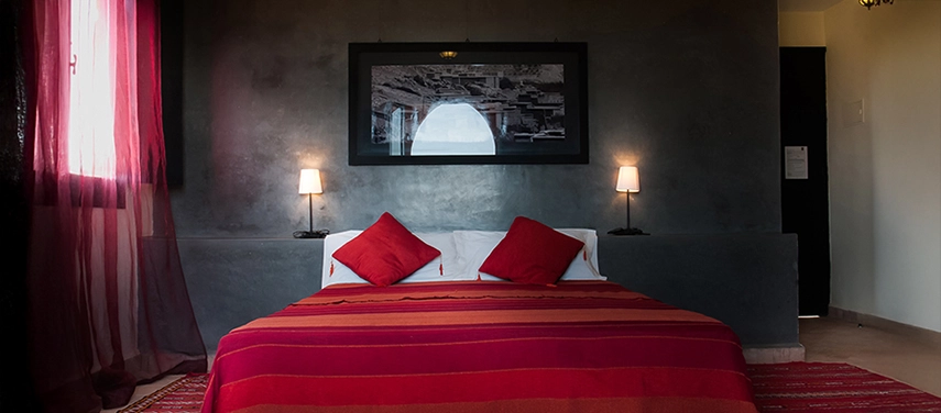 Double room with deep red striped bedspread, dark feature wall, and warm bedside lamps.