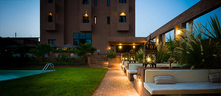Evening view of the garden terrace with glowing lanterns and poolside seating.
