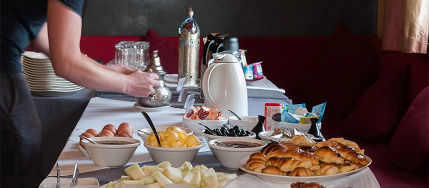 Breakfast buffet spread with fresh fruit, pastries, eggs, and Moroccan tea.