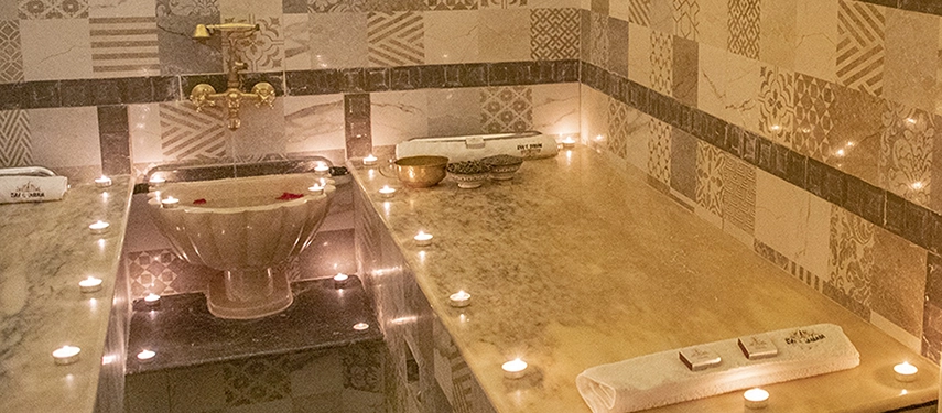 Serene hammam room at Ksar El Kabbaba with marble benches, tiled walls, and candlelight creating a tranquil spa atmosphere.