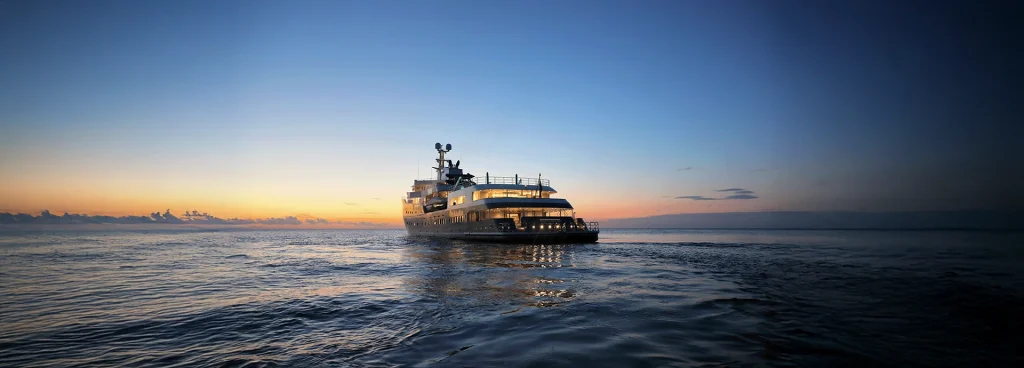 Aqua Lares illuminated at dusk as the sun sets over calm open seas.