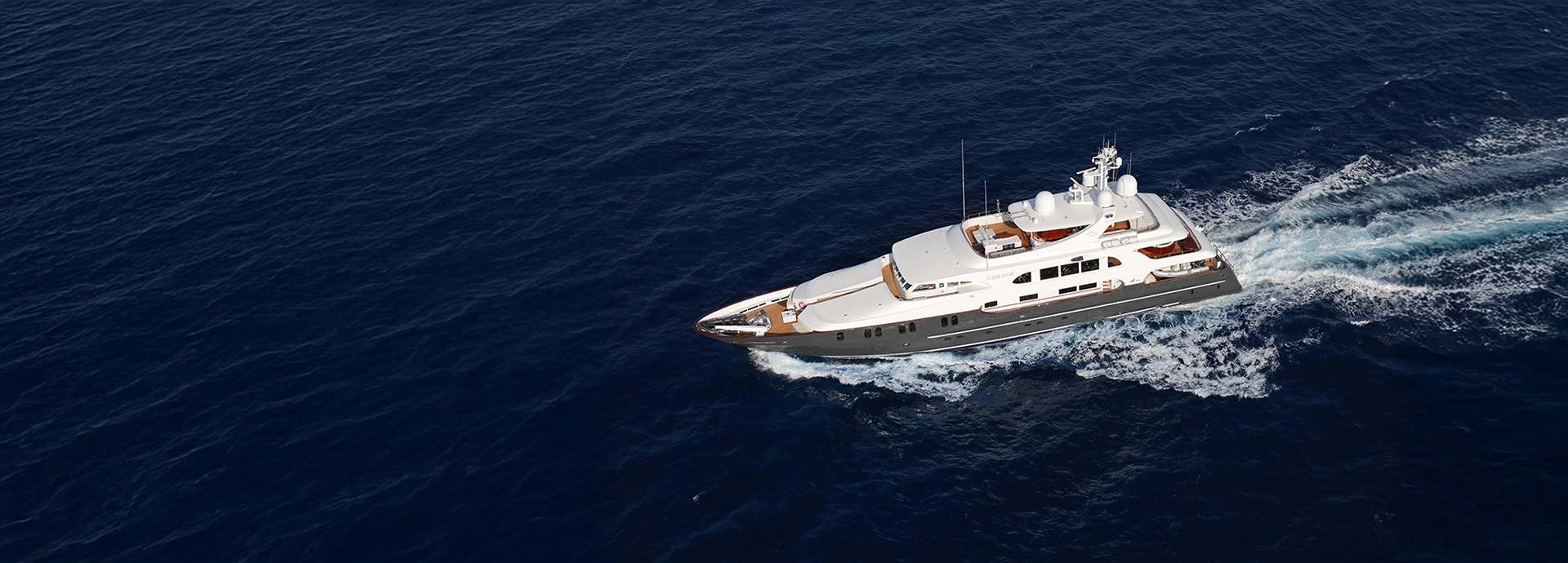 An aerial view of Aqua Mare cutting through the deep blue Pacific, her teak decks gleaming in the sunlight.