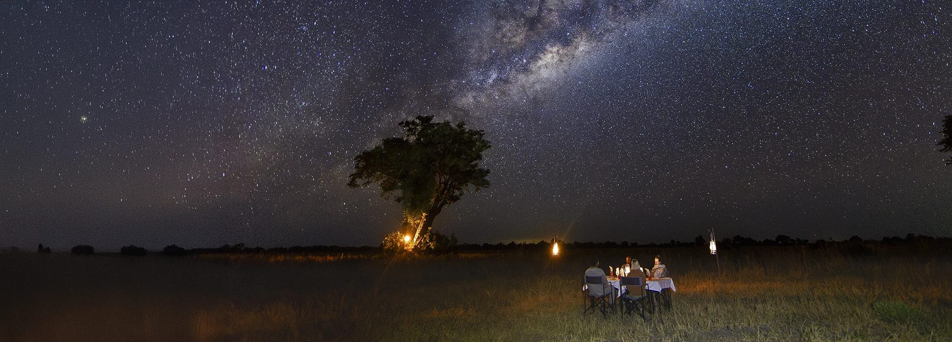Romantic lantern-lit dinner set beneath the vast night sky at Kweene River Camp.