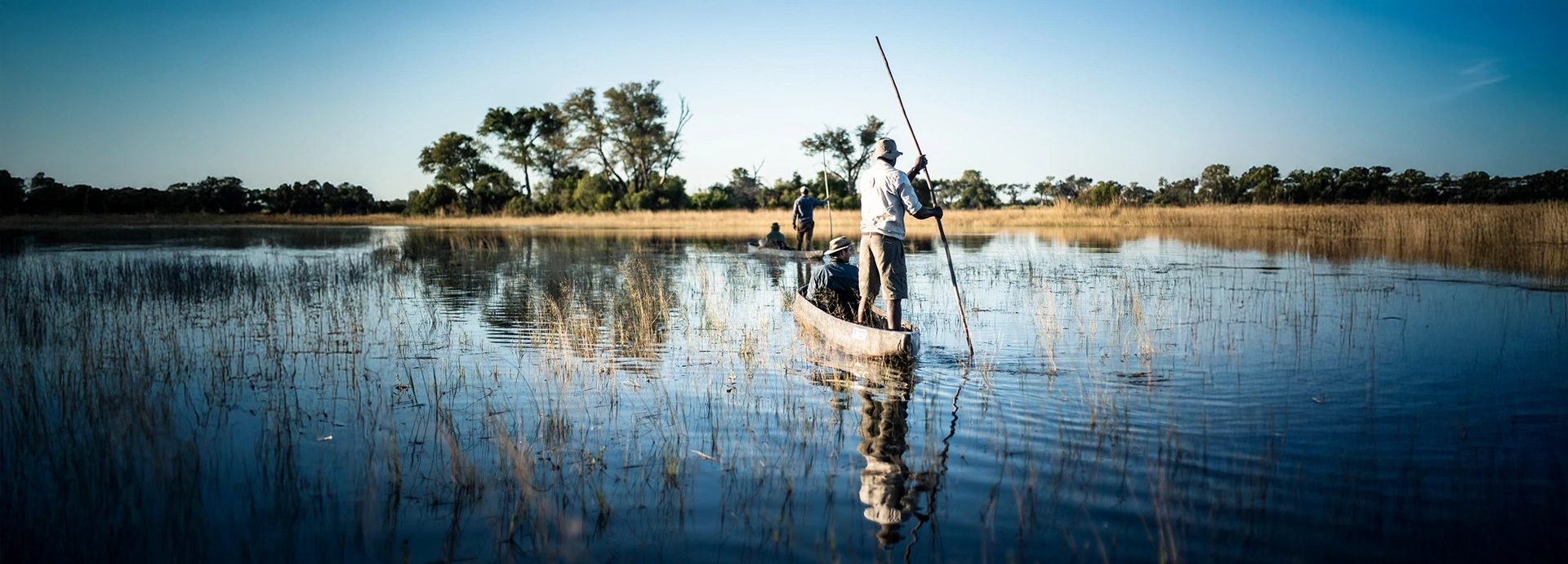 A mokoro safari cuts a gentle path through reflective delta waters, offering an intimate perspective of the Okavango landscape.