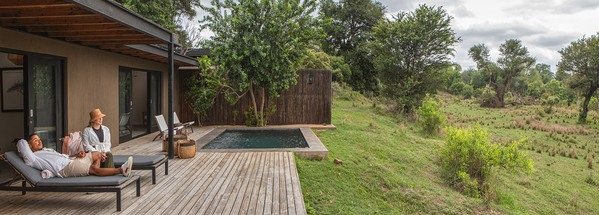 Couple relaxing on a private deck at Lion Sands River Lodge with plunge pool and river views.