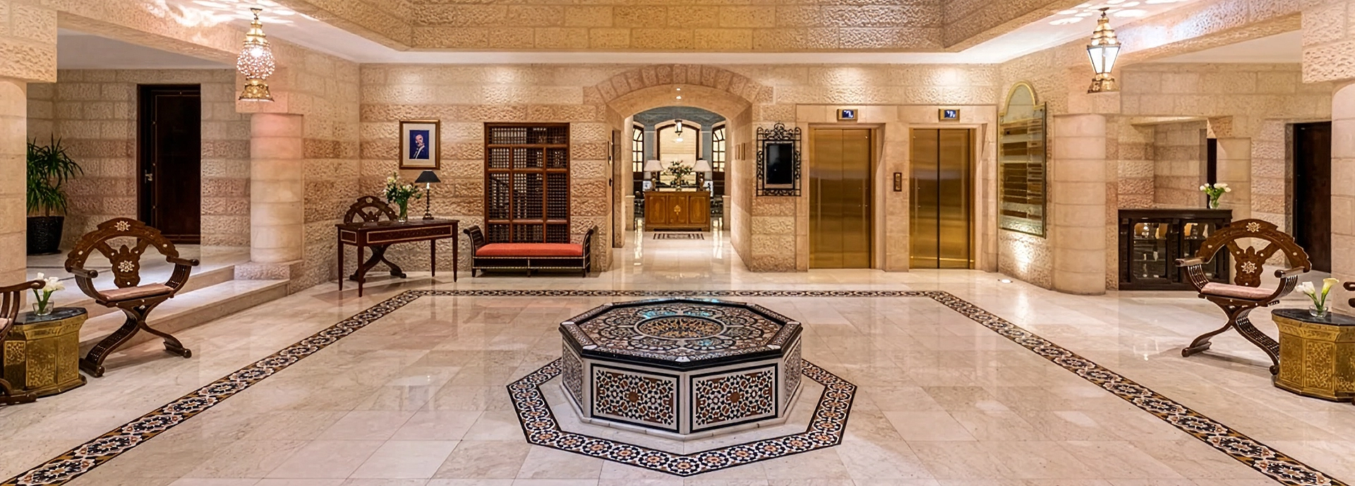 The elegant central courtyard of Mövenpick Hotel Petra features carved stone walls, traditional furnishings and a decorative mosaic fountain.
