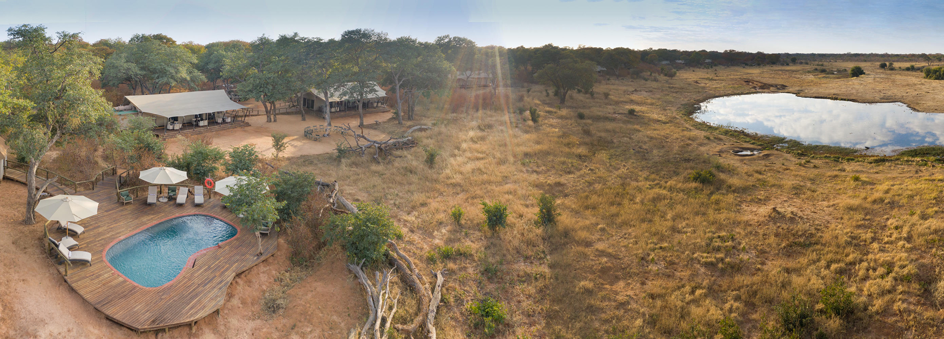 Aerial view of Verney’s Camp showing the main tents, pool deck and waterhole set in the Zimbabwean bush.