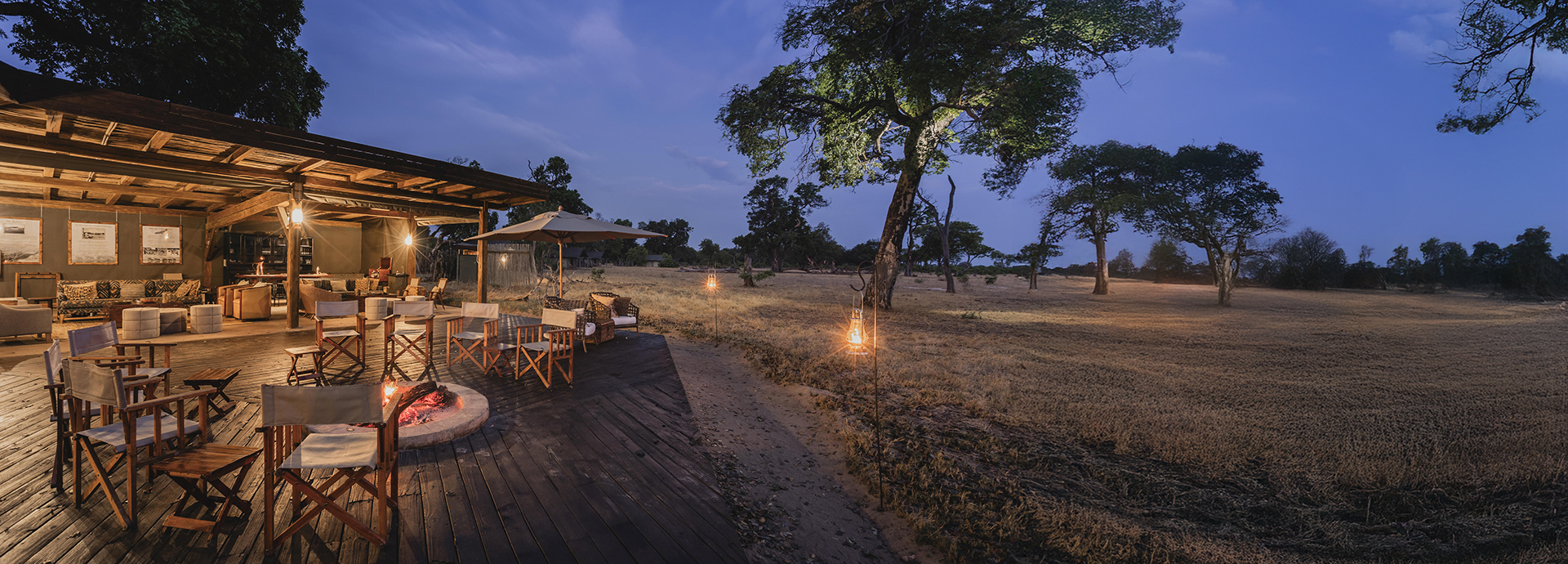 Evening view of Davison’s Camp firepit and lounge area under lantern light