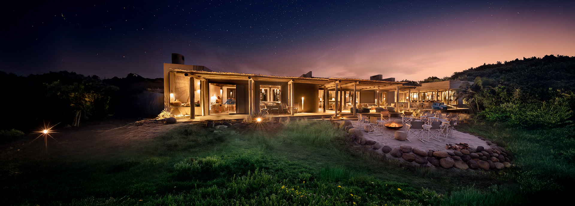 Wide view of the main lodge area at night with glowing lights and open seating under the stars.