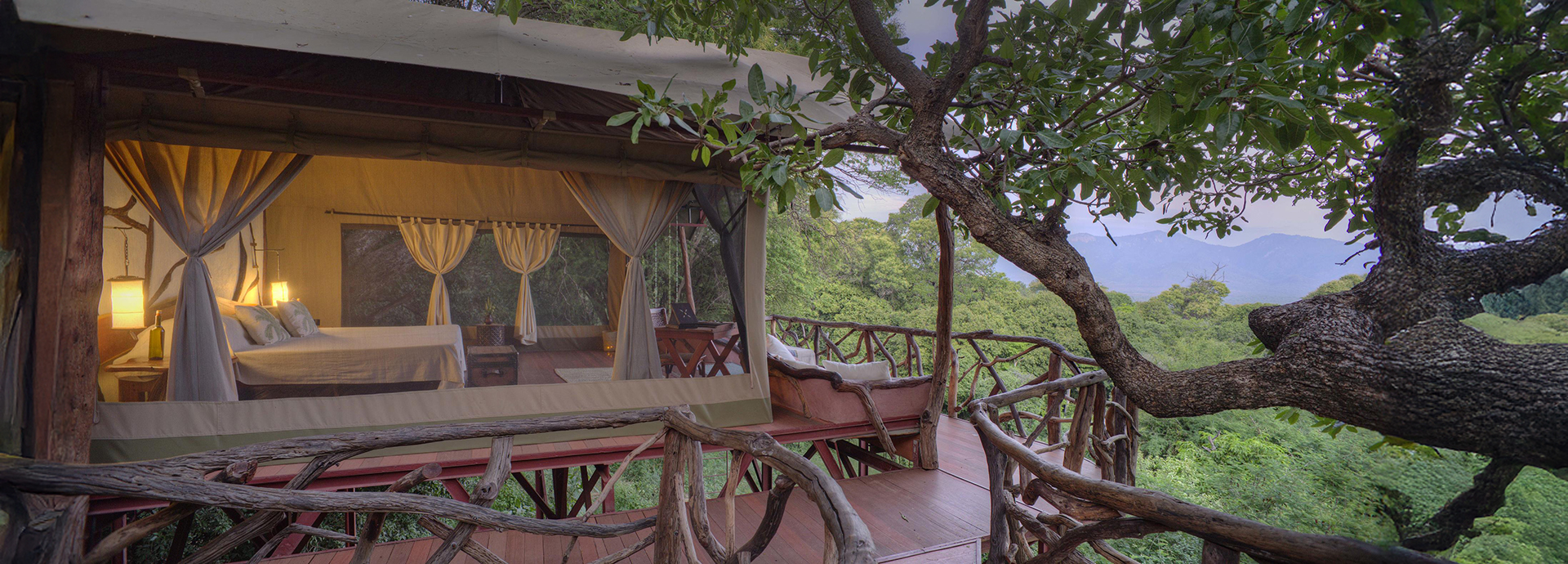 A raised canvas suite at Sarara Treehouses with ambient lighting, forest surroundings, and a private deck tucked among the trees.