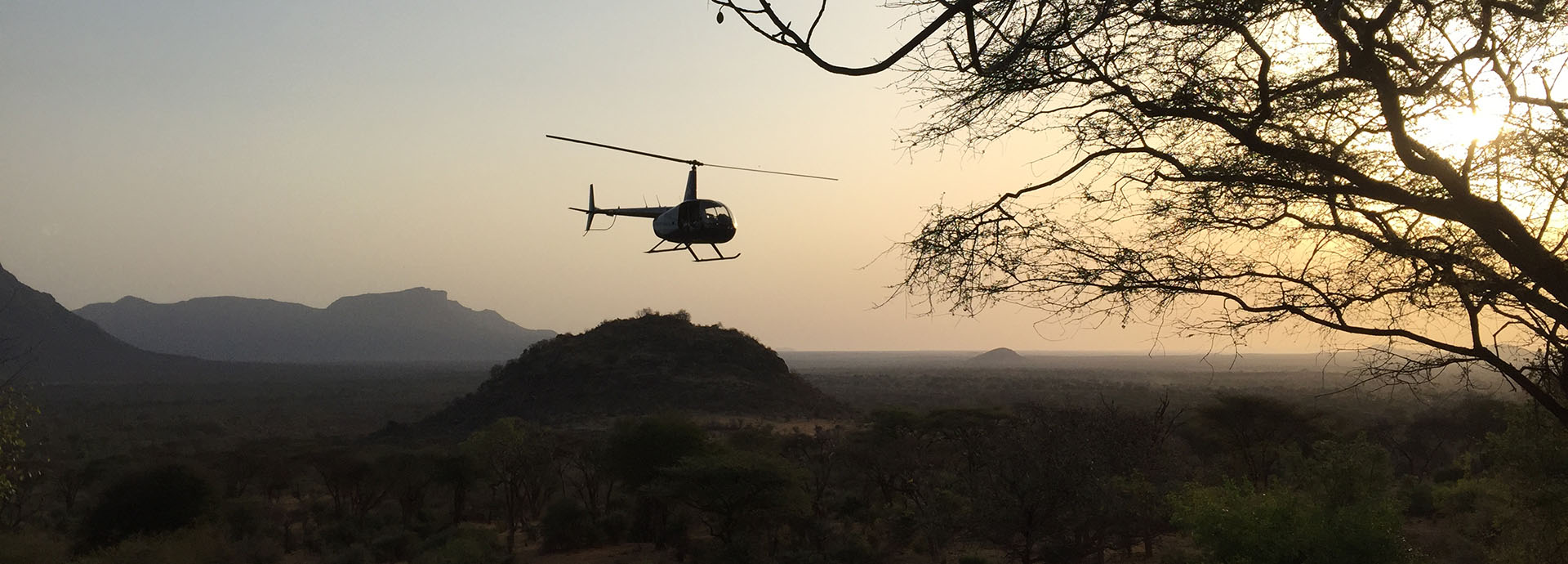 Helicopter flying over Kenya's Mathew Range at sunset