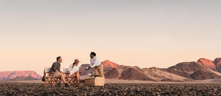 Tourist couple is served snacks by a waitress at Kulala Desert Lodge, Namibia
