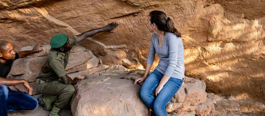 Tourist viewing ancient rock art with a guide in Hwange National Park