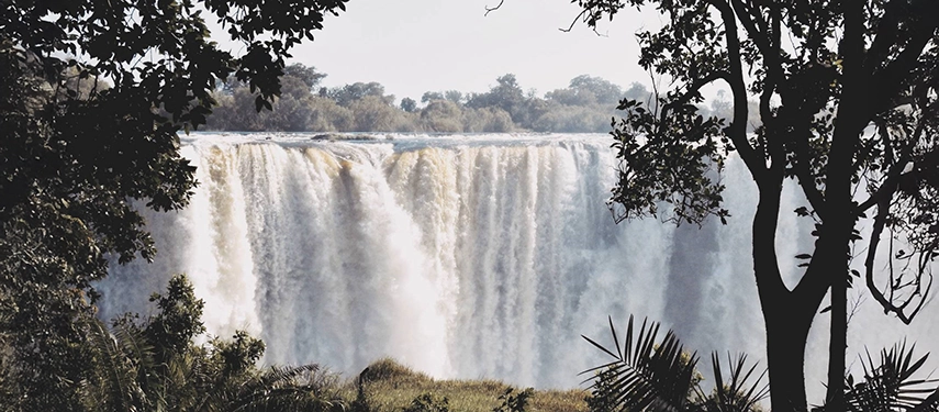 View of the mighty Victoria Falls framed by trees and vegetation near Insika Lodge.