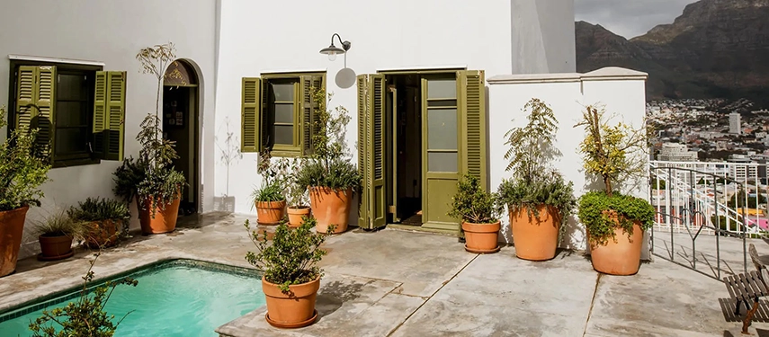 Charming courtyard at Dorp Hotel with terracotta pots, green shutters, and a plunge pool overlooking Cape Town.